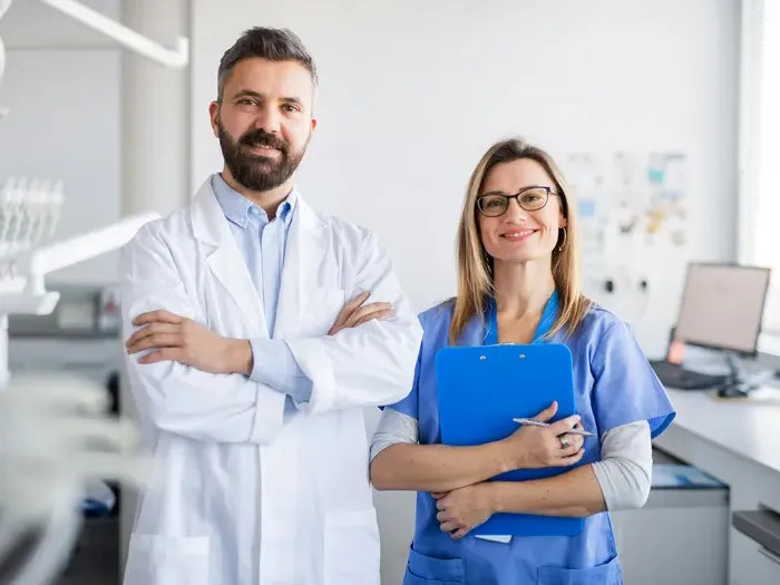 Friendly male and female medical professionals standing together in a bright modern clinic office